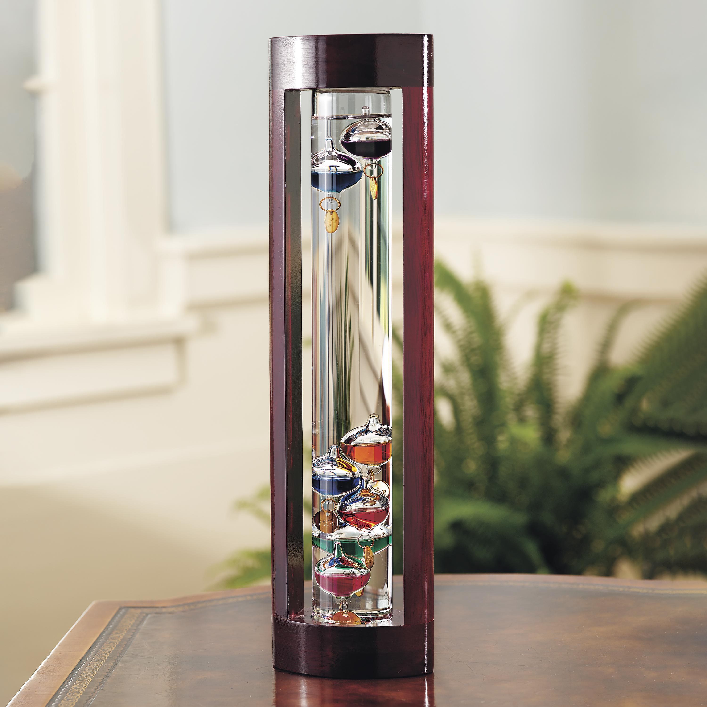 Galileo thermometer with colorful glass bubbles in liquid giving